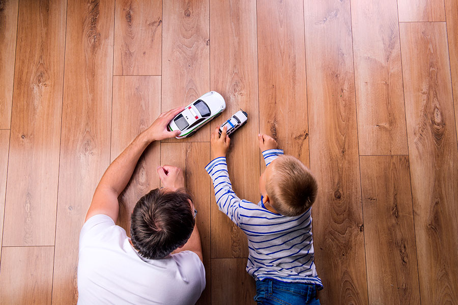Insurance Quote - View of Father and Son Playing with Toy Cars Across a Wooden Floor at Home